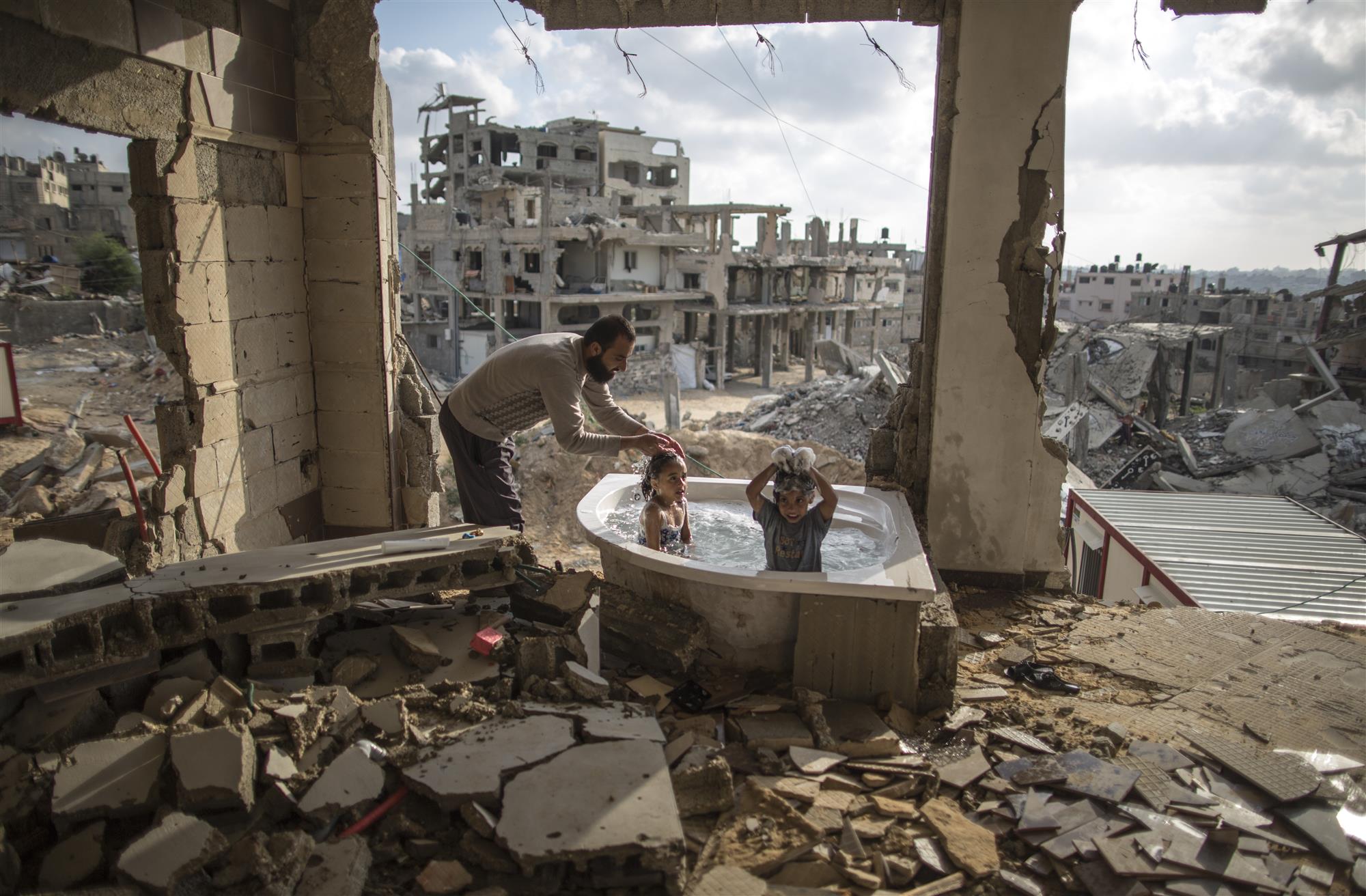 June 26, 2015  .Salem Saoody, 30, is getting his daughter Layan (L) and his niece Shaymaa 5 (R) in the only remaining piece from their damaged house, which is the bathing tub. They now live in a caravan near the rubbles. By Wissam Nassar.